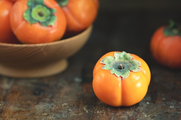 Herfstoogst Persimmon-vruchten in kom op een houten tafelachtergrond Kopieer ruimte Donkere rustieke stijl Natuurlijke remedie