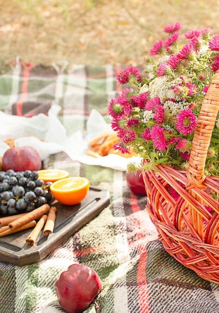 Herfstpicknick in het park, warme herfstdag. Mand met bloemen op een deken. Thee, croissants, koekjes, druiven in gele herfstbladeren. Herfst concept.