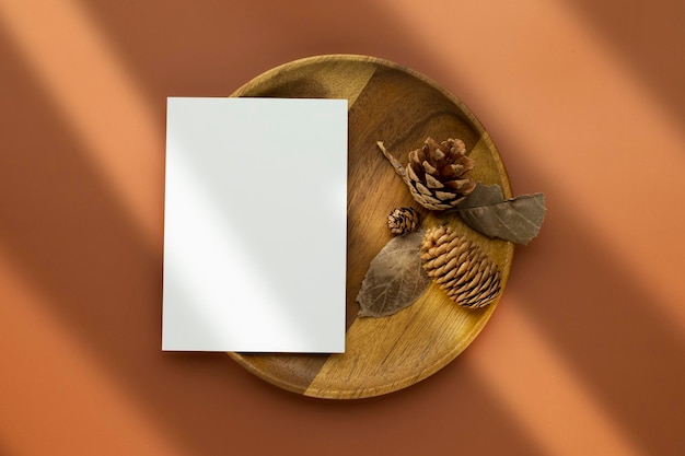 Herfstsamenstelling Blanco papieren kaarten Mockup met gedroogde bladeren en dennenappels op bruine achtergrond Platliggend bovenaanzicht met kopieerruimte