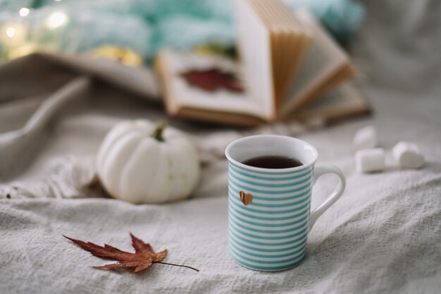 Herfststilleven met een koffiekopje bloemen en pompoenen op een gezellige plaid