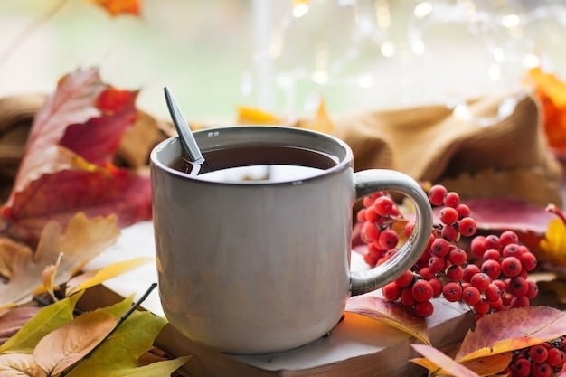 Herfststilleven met een mooie bokeh. Herfstbladeren en een kop hete dampende koffie of thee, sinaasappelpompoenen en een herfstoogst. Seizoensgebonden, ochtendkoffie, concept van stilleven, mock-uplay-out