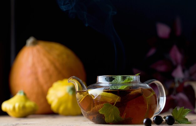 Herfstthee met citroenkruiden en bessen in een theepot op de achtergrond van pompoenen en squas...