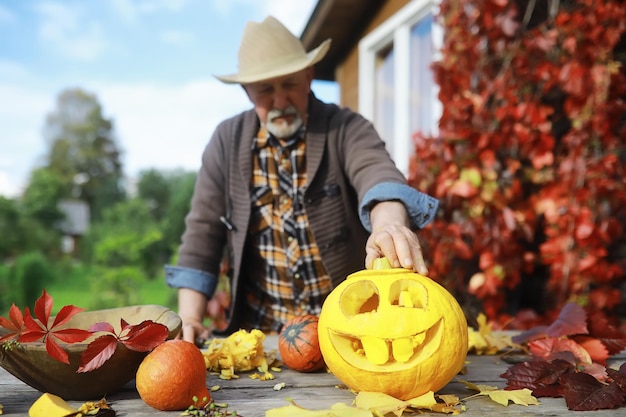 Herfsttradities en voorbereidingen voor de vakantie Halloween. Een huis in de natuur, een lamp gemaakt van pompoenen knipt uit aan tafel.