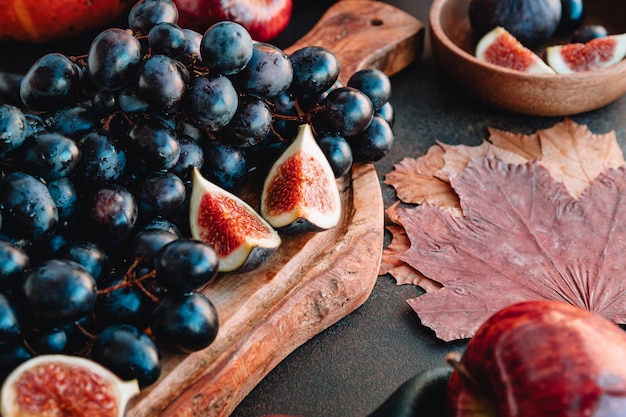 Herfstvoedselstilleven met seizoensfruit en groenten zoals Bangalore blauwe druif rode appels en vijgen op een tafel