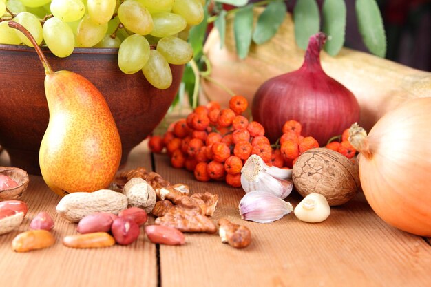 Herfstvruchten, groenten, noten en bessen in een kleiplaat op een houten ondergrond Veganistisch eten op een houten tafelclose-up