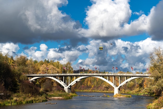 Herfstzicht op de Gauja-rivier en een brug erover met een kabelbaan over de vallei in Sigulda, Letland