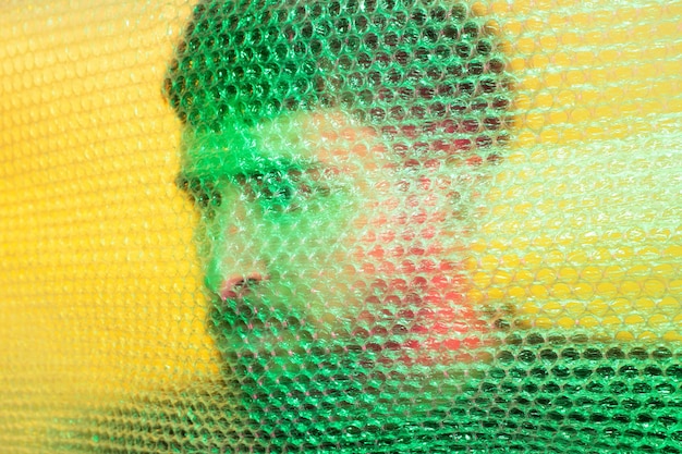 Foto hergebruik van plastic milieubescherming kunstportret man silhouet in duisternis aanraken van noppenfolie muur op gele achtergrond met kleurrijk licht het idee van ecologische duurzaamheid