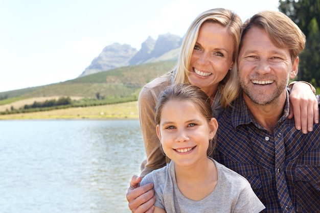 Herinneringen die een leven lang meegaan Portret van een gelukkig gezin van drie dat samen aan een meer zit