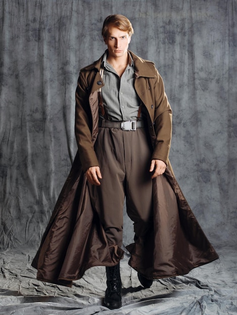 Hero in a military style with a gun in his hands a young man in a long brown coat and breeches with