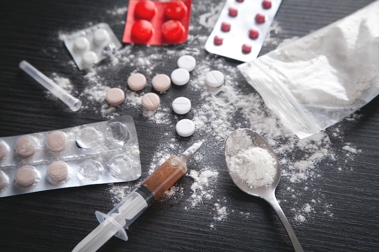 Photo heroin powder, pills and syringe on the dark background.