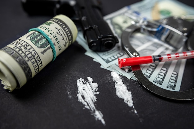 Heroïnedrug verspreidde volgende spuiten met wapens van gelddollars geïsoleerd op donkere achtergrond