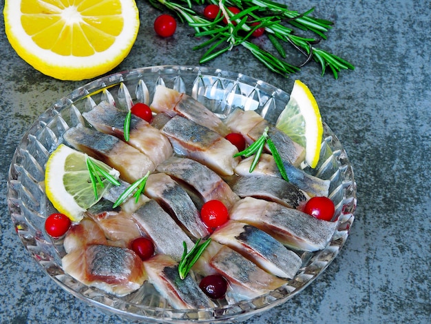 Herring with cranberries and rosemary. Pieces of herring in a crystal dish.