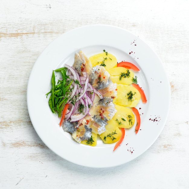 Herring with potatoes and onions on a plate. Ukrainian traditional cuisine. Top view. Free space for your text.