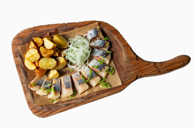 Herring with potatoes and onions on a wooden board.