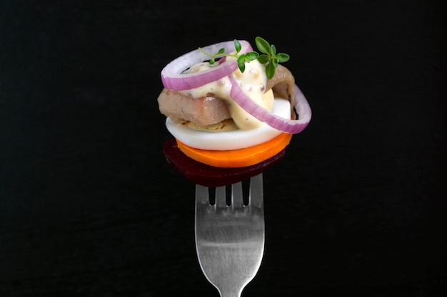 Herring with vegetables on a fork.