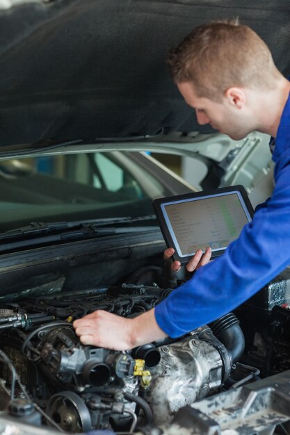 Hersteller met tabletpc die motor van een auto herstelt