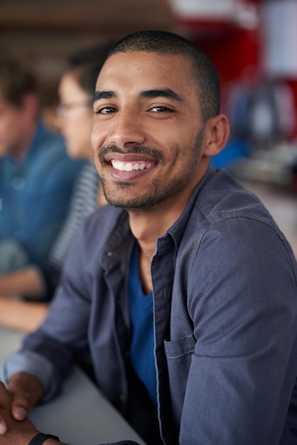 Hes an asset to the comapny Portrait of an handsome young man sitting in an office with colleagues in the background