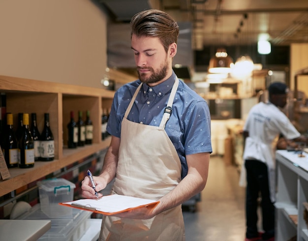 彼は彼のビジネスを管理している彼の商品を数えている若いビジネスオーナーのショット