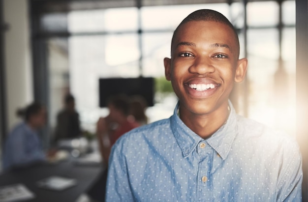 Hes an expert in the business Portrait of a young businessman standing in an office with colleagues in the background