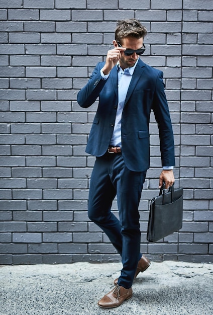 Hes got the look Shot of a handsome young businessman standing against a grey facebrick wall