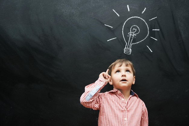 Hes got a lot of ideas Studio shot of a young boy with a chalkdrawing light bulb above his head