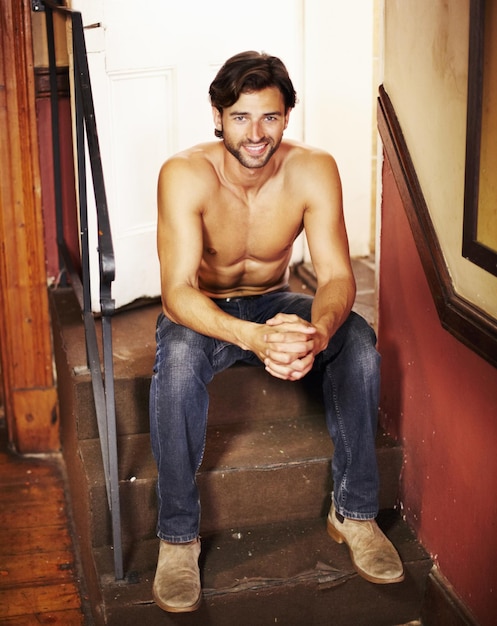 Hes got plenty of rugged charm Attractive young man relaxing on a staircase with a smile