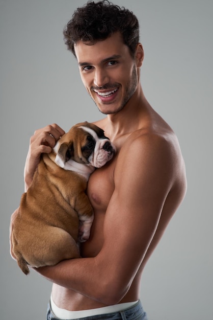 Hes the perfect package handsome and caring Studio shot of a handsome young man posing with his puppy against a grey background