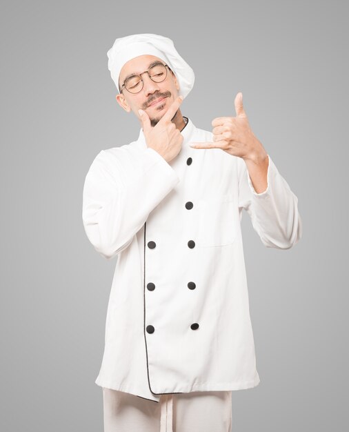 Hesitant young chef making a gesture of calling with the hand