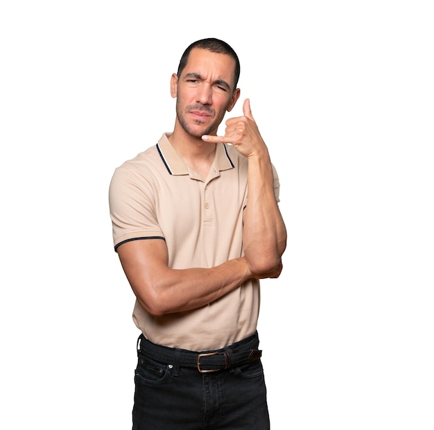 Hesitant young man making a gesture of calling with the hand