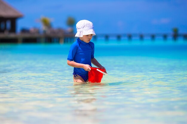 Het aanbiddelijke meisje spelen met strandspeelgoed tijdens tropische vakantie