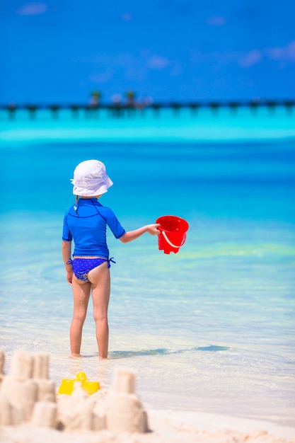 Het aanbiddelijke meisje spelen met strandspeelgoed tijdens tropische vakantie