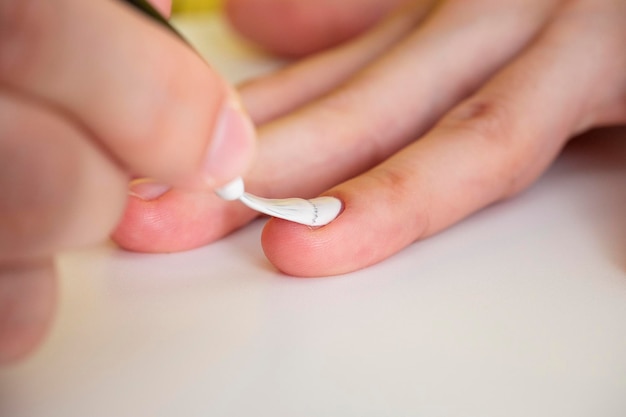 Het aanbrengen van witte nagellak op de nagel. Manicure- en nagelverzorgingsconcept