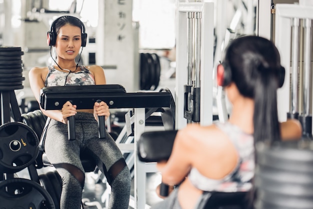 Foto het aantrekkelijke jonge opheffende gewicht van de sporten aziatische vrouw in gymnastiek.