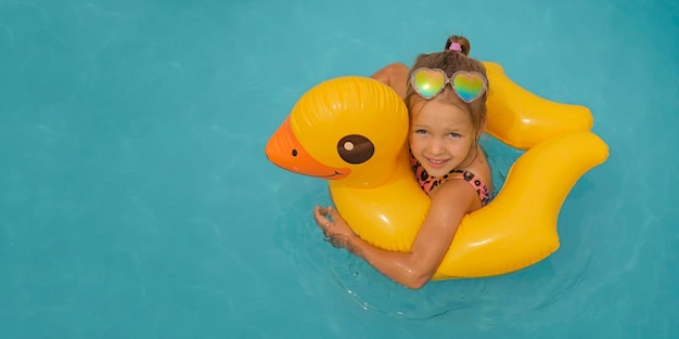 Het aantrekkelijke mooie meisje zwemt in water in reddingsboei in vorm van eend