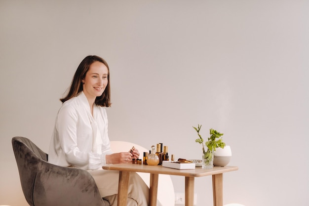 Het aromatherapeut-meisje zit in haar kantoor, er liggen essentiële oliën op tafel