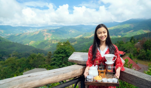 Het Aziatische meisje ontspant met hete cofee en heet theestel op meningspunt van doi sakad