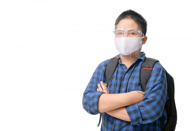 Het Aziatische schild en het masker van het de slijtagegezicht van de jongensstudent dragen geïsoleerde schooltas