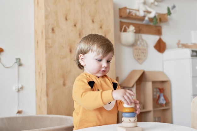Het babykind speelt met houten speelgoedpiramide Vroege ontwikkeling