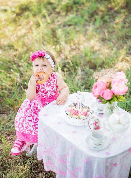 Het babymeisje viert haar eerste verjaardag met cake en ballons in aard