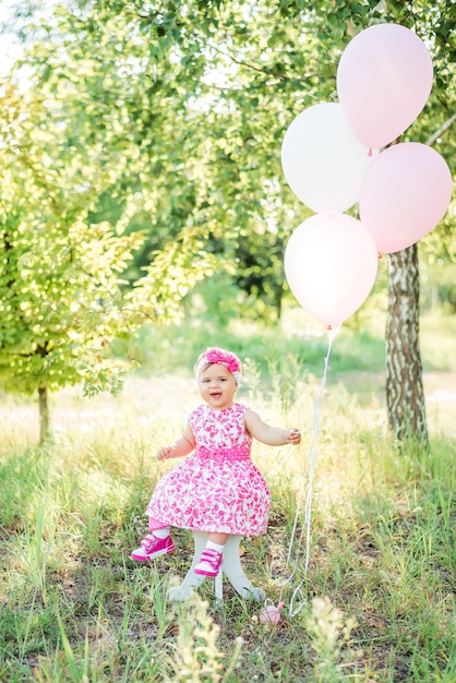 Het babymeisje viert haar eerste verjaardag met cake en ballons in aard