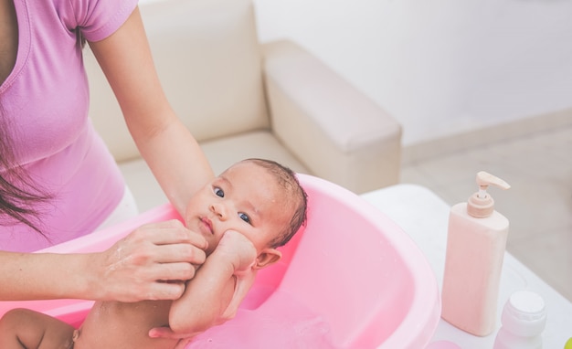 Foto het babymeisje wordt gebaad door zijn moeder