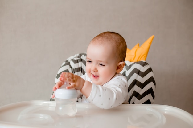 Het babymeisje zit als voorzitter van een kind met een waterfles