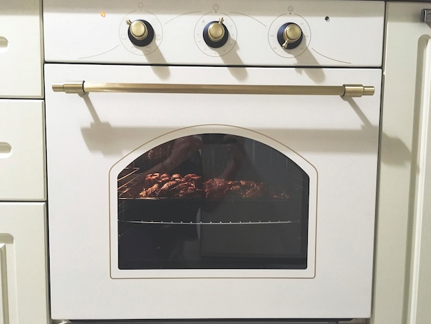 Foto het bakken van vlees in een witte oven