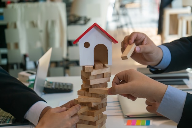 het balanceren van de vastgoedsector in zaken, handen en een houten huis