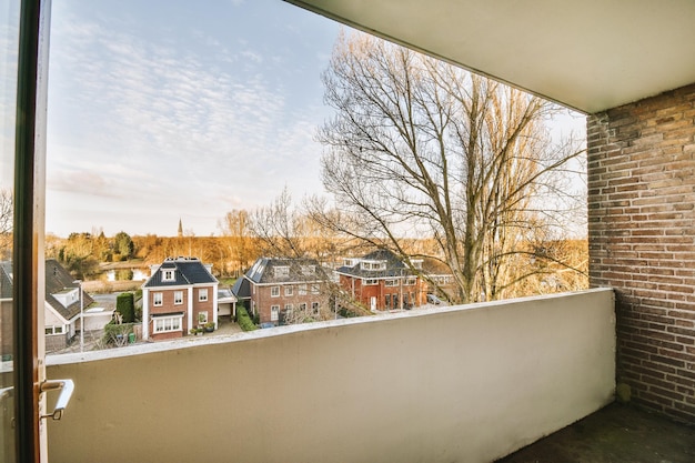 Het balkon van een bakstenen gebouw met een betonnen hek en uitzicht op een stadslandschap