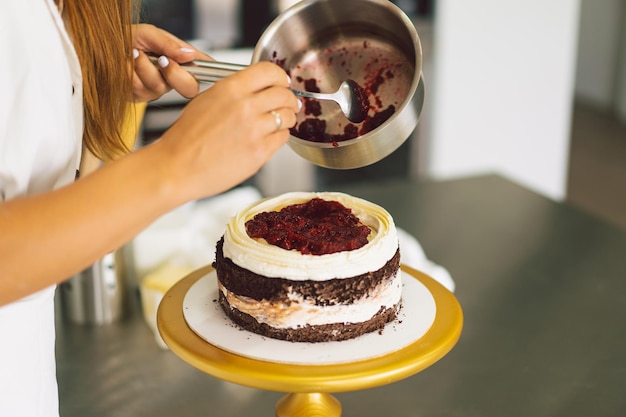 Het banketbakkersmeisje bereidt een cakekoekje met witte room en chocoladekoekjes voor