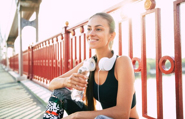 Het beetje water tijdens sportoefeningen. Vrouw drinkt water terwijl ze uitrust na ochtendrennen