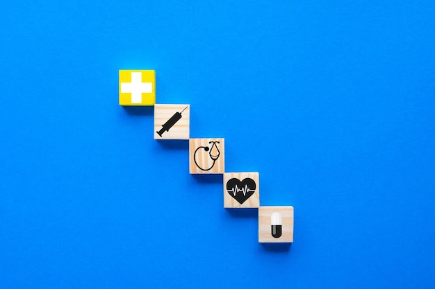Het begrip ziektekostenverzekering, kopieer ruimte op een blauwe houten kubus met medische symbolen voor de gezondheidszorg op een blauwe achtergrond.