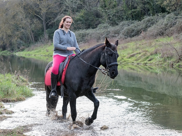 Het berijdende meisje leidt haar zwarte paard op