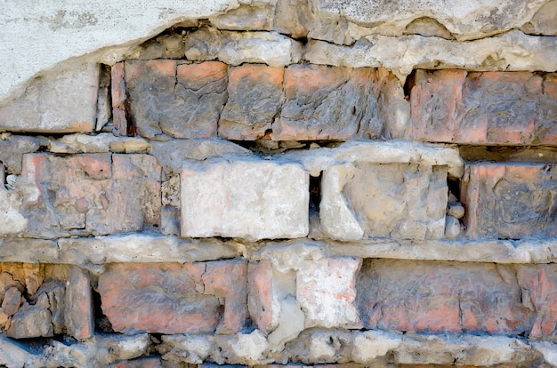 Het betonnen oppervlak met een grote steen en oude baksteen